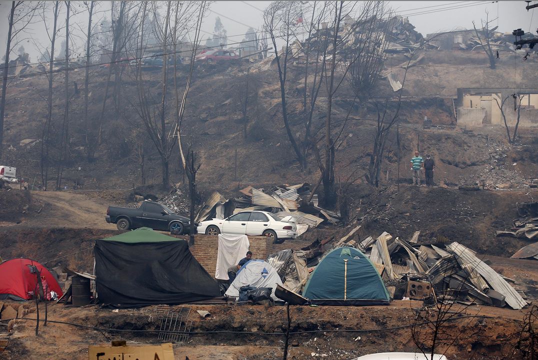 Un grupo de personas descansan en carpas luego de que sus casas fueran arrasadas por un incendio forestal. EFE