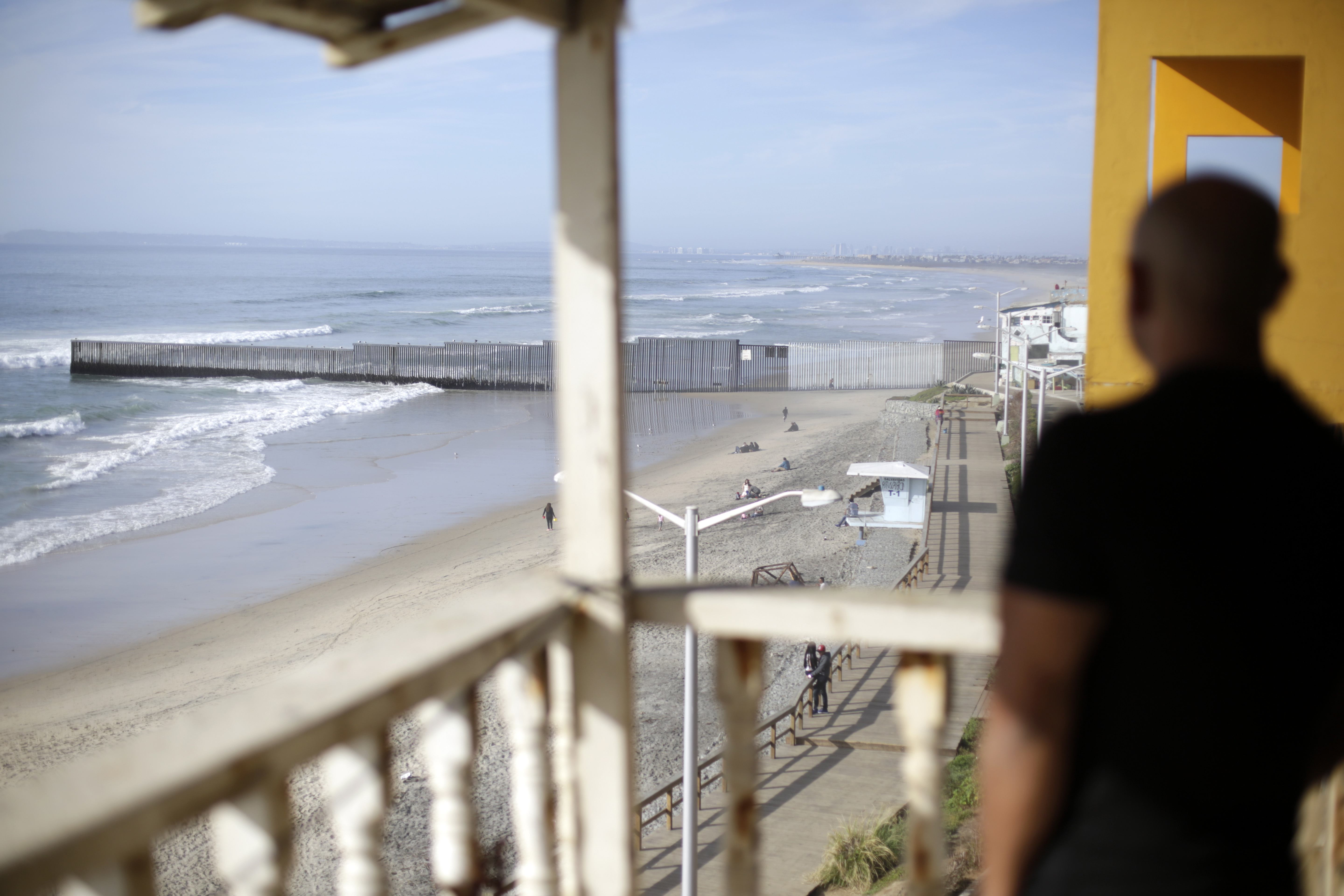 El veterano de los Estados Unidos, Antonio Romo, que fue deportado, mira desde su balcón de apartamentos en Tijuana, México, donde puede ver el muro fronterizo estadounidense que separa San Diego. AP