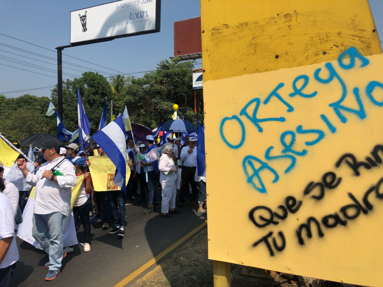 La marcha al lado de los llamados árboles de la vida oficialistas. Aquí, al pie de uno de estos árboles conocidos popularmente como "chayopalos", una pinta de otras protestas denuncia: "Ortega asesino". LA PRENSA / Fabrice Le Lous