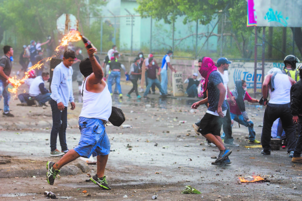 Manifestantes combaten con las fuerzas antimotines en semáforos de la Miguel Gutiérrez