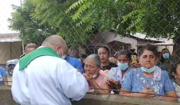 Policía impide ingreso de feligreses a parroquia y sacerdote realiza misa otorgando la eucaristía a través de una cerca