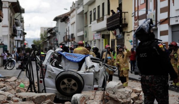 Un policía mira hacia un automóvil aplastado por los escombros después de que un terremoto sacudiera Cuenca, Ecuador, el sábado 18 de marzo de 2023. (AP Foto/Xavier Caivinagua)