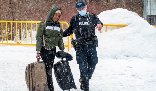 Getty Images Policía canadiense guía a una mujer en Roxham Road antes del cierre.