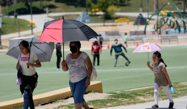 Los visitantes se cubren del calor con sombrillas a medida que aumentan las temperaturas en MacArthur Park, el martes 11 de julio de 2023 en Los Ángeles. (Foto AP/Marcio José Sánchez)