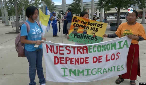 La guatemalteca Lucía Quié (derecha) posa junto a sus hijas portando un cartel que reza "nuestra economía depende de los inmigrantes" durante la marcha organizada en este sábado 1 de julio en Homestead, Florida, contra la ley SB 1718.