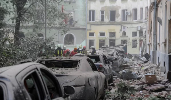 Trabajadores de los servicios de emergencia se reúnen frente a los edificios dañados mientras continúa la búsqueda de víctimas tras un ataque con misiles rusos en Lviv, Ucrania, el 6 de julio de 2023.