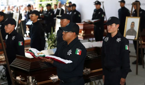 ARCHIVO - La policía vigila junto a los ataúdes que contienen los restos de 13 policías mexicanos asesinados en una aparente emboscada de un cartel, durante un servicio conmemorativo en Morelia, México, el 15 de octubre de 2019.