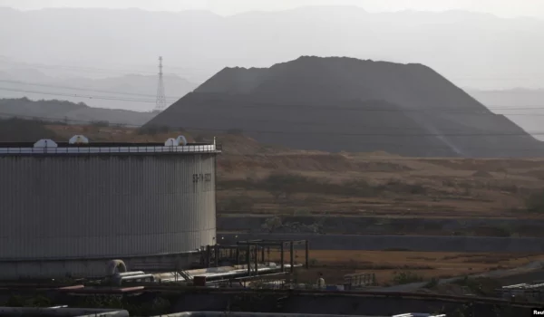 ARCHIVO - Un montículo de coque se ve junto a un tanque de petróleo en el complejo industrial José Antonio Anzoátegui de PDVSA en el estado de Anzoátegui, en Venezuela, el 15 de abril de 2015