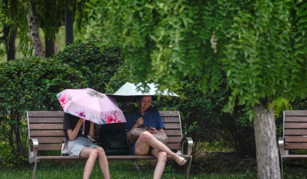 Dos mujeres se cubren del sol durante un día caluroso en Beijing, el 3 de julio de 2023