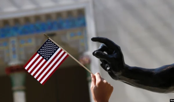 ARCHIVO - Una niña sostiene una bandera estadounidense junto a una escultura después de una ceremonia de naturalización en el Museo Metropolitano de Arte de Nueva York el 22 de julio de 2014.