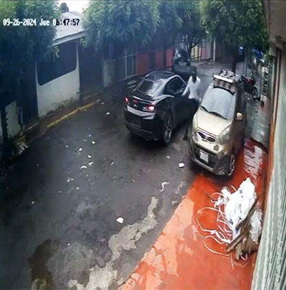 En esta otra imagen uno de los ladrones del carro negro busca como forzar la puerta de un vehículo estacionado en la vía pública. LA PRENSA/ Redes sociales captura de video.