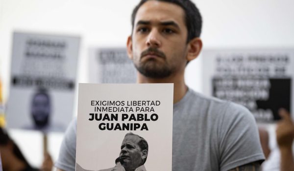Ramón Guanipa sostiene un cartel de su padre detenido, Pedro Guanipa, en una imagen reciente. . EFE/Ronald Peña R