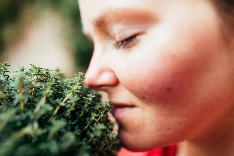 Chica oliendo una planta medicinal
