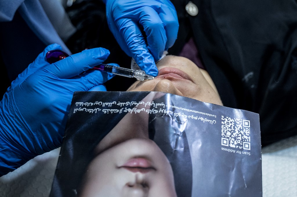 Doctora inyectando botox en labios de paciente afgana
