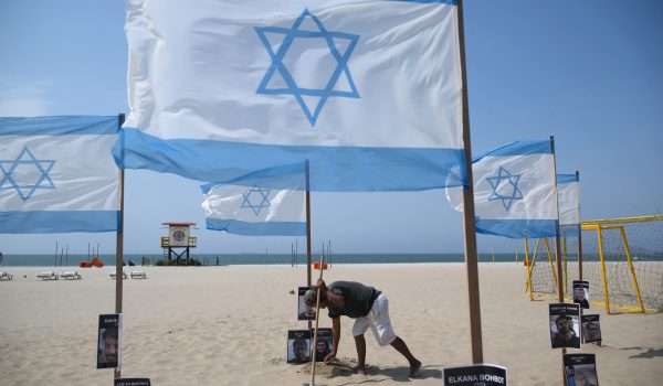 Un miembro de la ONG brasileña Río de Paz instala una bandera israelí junto a los nombres de las víctimas, en conmemoración del segundo aniversario de los ataques de Hamás (Foto de MAURO PIMENTEL / AFP)