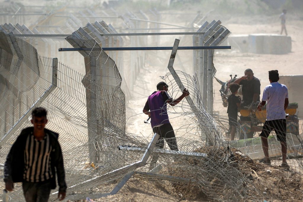 Un hombre intenta retirar la valla y las barreras en el llamado "corredor Netzarim", cerca de Nuseirat, en el centro de la Franja de Gaza. (Foto de Eyad BABA / AFP)