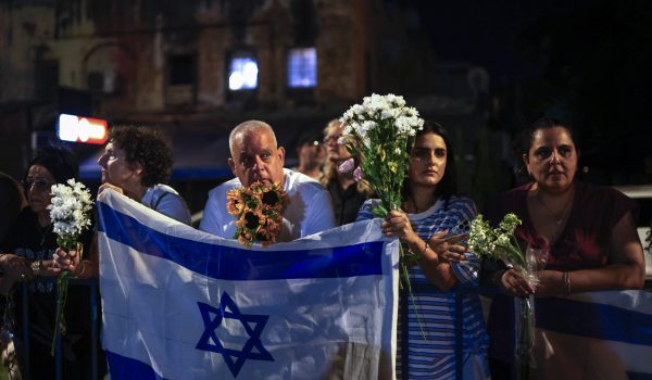 Personas portan flores y banderas israelíes a la llegada de vehículos que transportan los cuerpos de cuatro rehenes entregados tras un acuerdo de alto al fuego. (Foto de Jalaa MAREY / AFP)