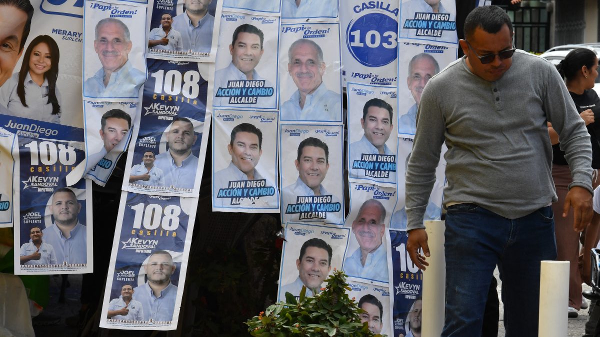 Un hombre pasa junto a la propaganda electoral durante las elecciones generales de Honduras en Tegucigalpa el 30 de noviembre de 2025. (Foto de Orlando SIERRA / AFP)