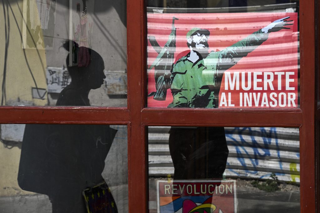 Una mujer pasa junto a un cartel del fallecido dictador cubano Fidel Castro con el lema "Muerte al invasor" en La Habana, el 13 de marzo de 2026