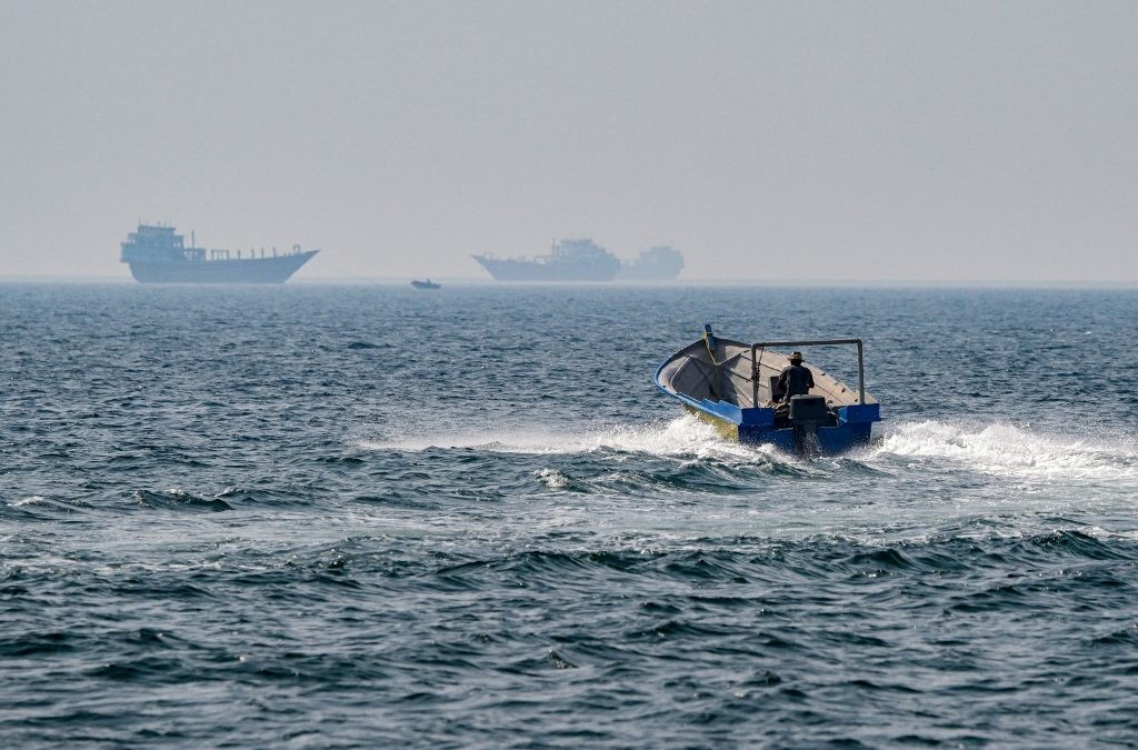 Una lancha y dos barcos navegan en aguas del estrecho de Ormuz. Washigton comenzó un bloqueo total de los puertos iraníes este lunes. AFP
