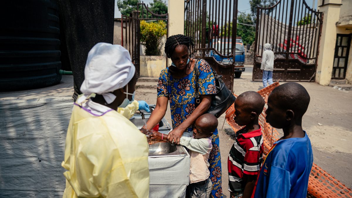 Una madre ayuda a sus hijos a lavarse las manos antes de entrar al Hospital Kyeshero en un punto de control para todos los visitantes y pacientes que ingresan al hospital, como parte de las medidas de prevención del Ébola en Goma el 18 de mayo de 2026. AFP/ JOSPIN MWISHA