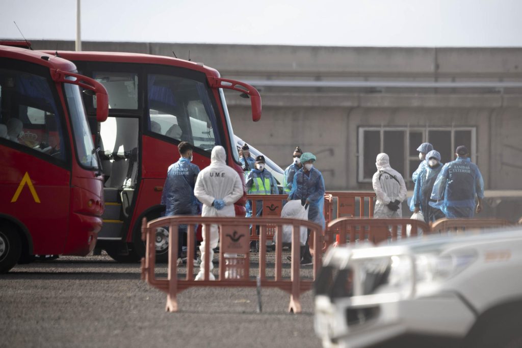 Dos de los pasajeros desembarcados que iban a bordo del crucero neerlandés MV Hondius han desembarcado ya en el puerto de Granadilla de Abona y reciben instrucciones de personal de la Unidad Militar de Emergencias y del Servicio de Sanidad Exterior. EFE/Miguel Barreto