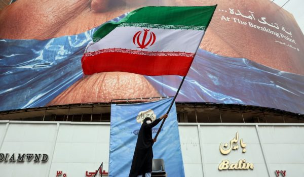 Una mujer ondea una bandera iraní frente a un cartel antiestadounidense que hace referencia al presidente de Estados Unidos, Donald Trump, y al Estrecho de Ormuz en la Plaza Valiasr de Tehran, el 5 de mayo de 2026. El principal negociador de Irán en las conversaciones con Estados Unidos advirtió el 5 de mayo que su país “ni siquiera ha comenzado” en su enfrentamiento por el Estrecho de Ormuz. (Foto de AFP)