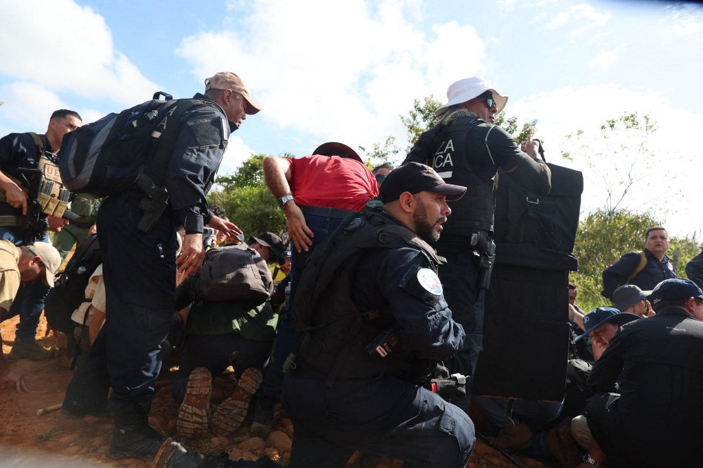 Agentes de seguridad agachados protegen con escudos a la presidenta de Costa Rica, Laura Fernández, y a sus acompañantes tras una explosión ocurrida esta mañana durante una visita a una zona minera ilegal en Crucitas, cerca de la frontera con Nicaragua. Randall SANDOVAL / GRUPO EXTRA / AFP