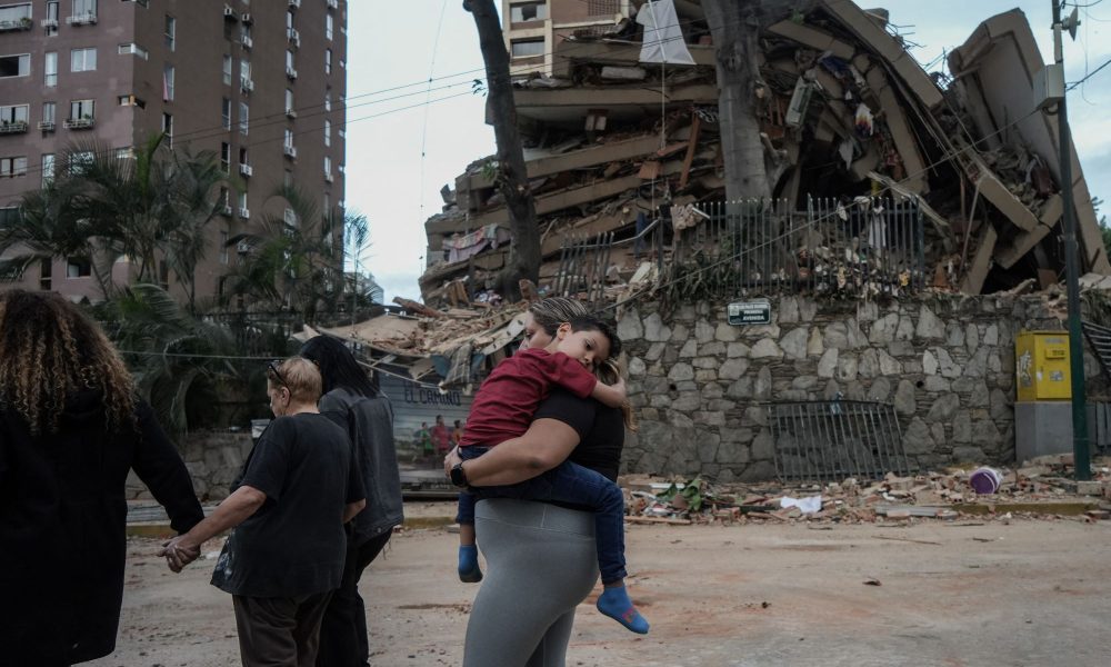 Una familia camina al lado de edificios derruidos en Caracas, tras dos terremotos consecutivos que estremecieron Venezuela el miércoles. MANAURE QUINTERO/AFP