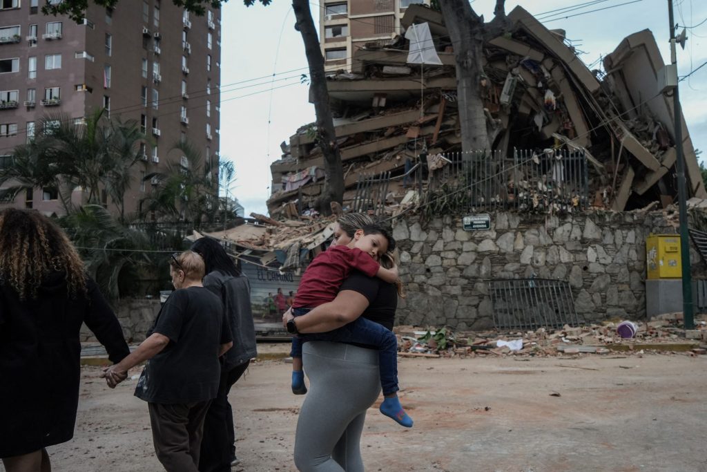Una familia camina al lado de edificios derruidos en Caracas, tras dos terremotos consecutivos que estremecieron Venezuela el miércoles. MANAURE QUINTERO/AFP
