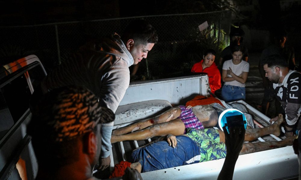 Dos cadáveres son colocados en una camioneta por habitantes de Catia La Mar, en la Guaira. Se reporta al menos 164 muertos en todo el país hasta la mañana del jueves. FEDERICO PARRA/AFP