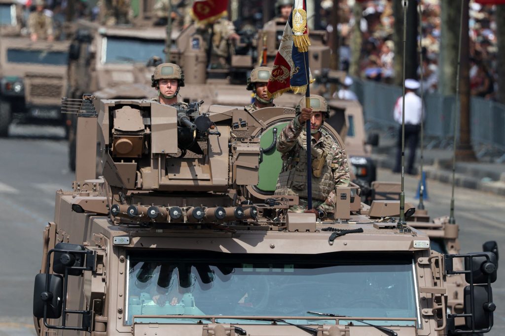 Miembros del 41.º Regimiento de Transmisiones de la CATNC conducen un vehículo blindado durante el tradicional desfile militar por el Día de la Bastilla, con la avenida de los Campos Elíseos al fondo, en París, el 14 de julio de 2026. AFP