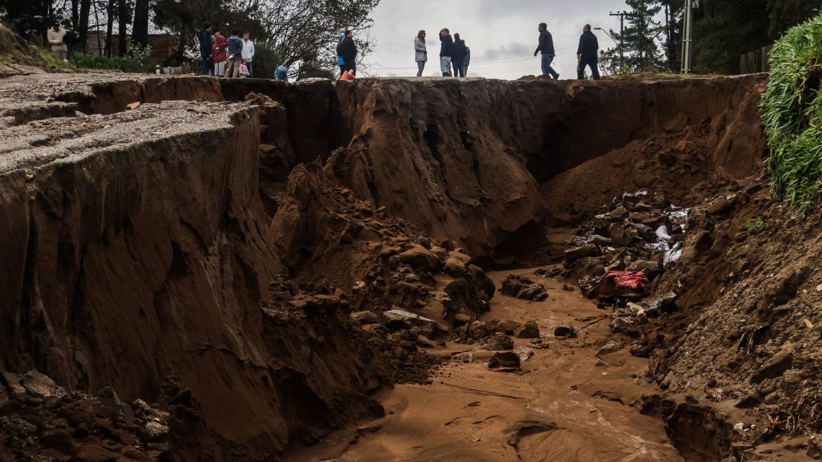 Varias personas se encuentran junto a un gran socavón formado tras las fuertes lluvias en Viña del Mar, Chile, el 18 de julio de 2026. Cinco personas fallecieron y miles resultaron afectadas por una tormenta con fuertes lluvias, marejadas ciclónicas y vientos que impactó a 10 de las 16 regiones del país. Cristobal Basaure / AFP