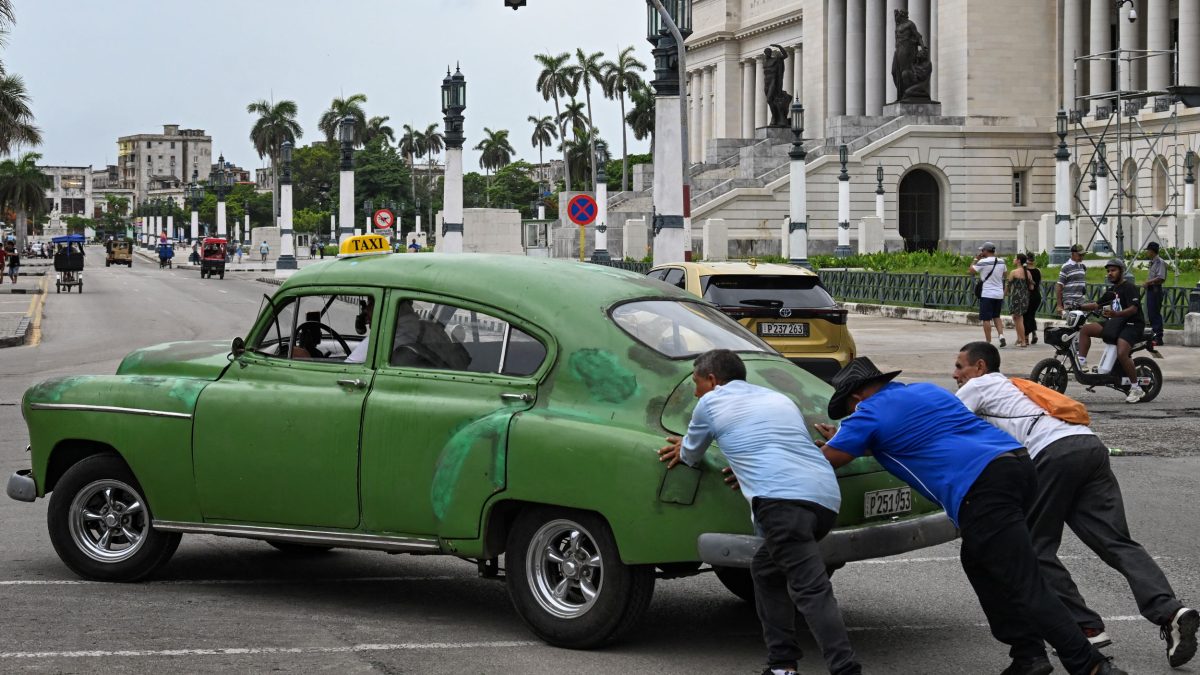 Unas personas empujan un coche antiguo por una calle de La Habana el 29 de julio de 2026. Cuba comenzó a liberalizar ciertos sectores de su economía, reduciendo drásticamente el número de actividades prohibidas a las empresas privadas. YAMIL LAGE / AFP