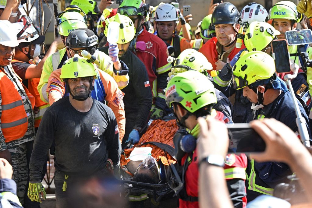 Los equipos de rescate, procedentes de varios países, aplaudieron a Hernán Gil al ser llevado fuera del edficicio donde fue rescatado. FEDERICO PARRA/AFP
