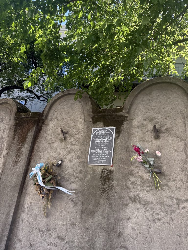 En la imagen se ve un fragmento del muro del gueto de Cracovia adornado con flores en señal de homenaje.