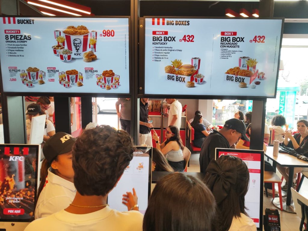 Clientes haciendo su pedido desde pantallas digitales en KFC Managua. Foto: Cortesía.