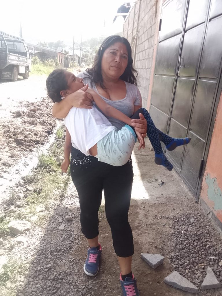 Rosalina Gutiérrez carga en brazos a su hija de 8 años para poder trasladar de un sitio a otro