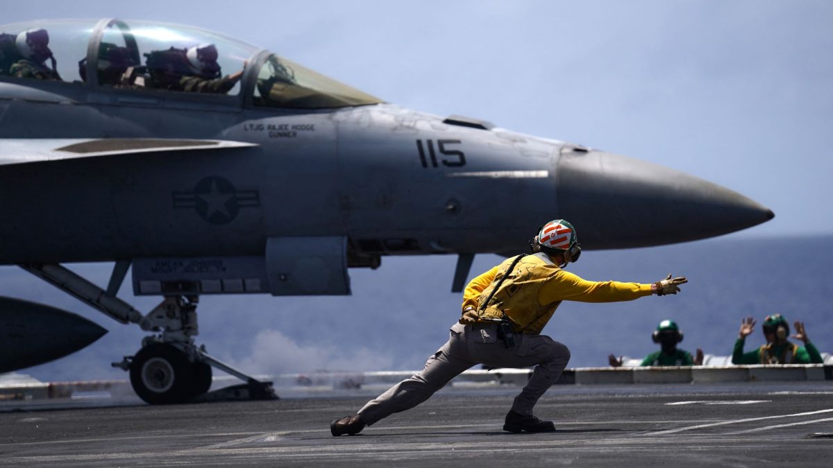 Un suboficial de aviación de la Armada de los Estados Unidos dirige un F/A-18F Super Hornet asignado al Escuadrón de Fuerza de Ataque (VFA) 154 en la cubierta de vuelo del portaaviones USS Theodore Roosevelt (CVN-71). Michelle Bir / AFP