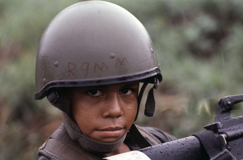 Un niño soldado de la Guardia Nacional, con el rostro mojado por la lluvia, porta un fusil M-16 de origen estadounidense y un casco israelí OR-201. La imagen corresponde a los últimos días de la guerra, en julio de 1979. LA PRENSA / MATTHEW NAYTHONS