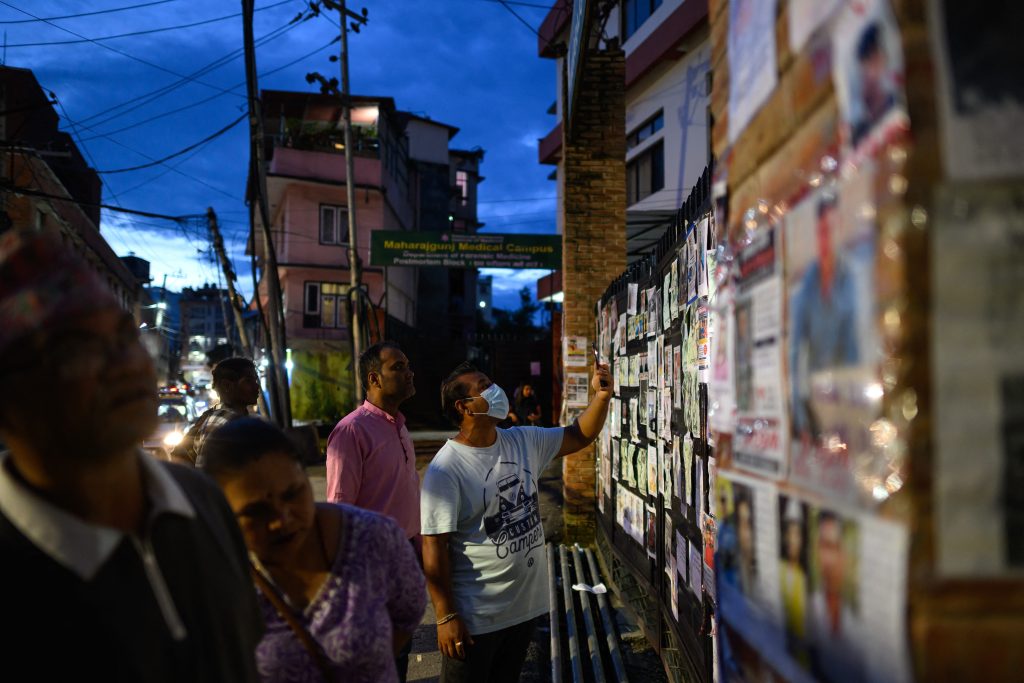 Personas observan fotografías de desaparecidos tras unas inundaciones repentinas, frente a un hospital de Katmandú el 30 de agosto de 2026. (Foto de MANAN VATSYAYANA / AFP)