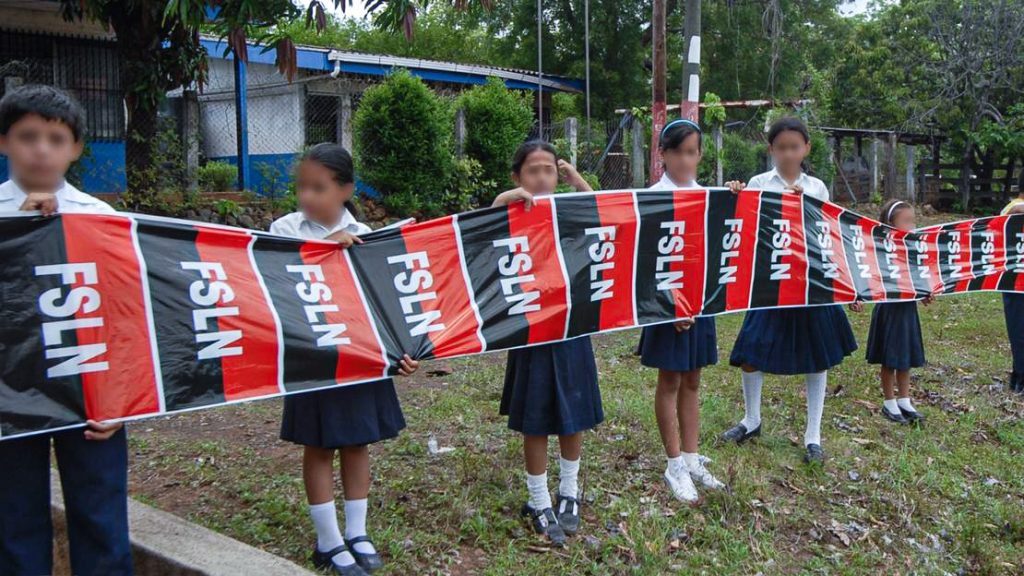 Estudiantes sostienen banderas del FSLN durante una visita de Daniel Ortega a Juigalpa. La presencia de símbolos partidarios en actividades con estudiantes continúa durante el actual gobierno. LA PRENSA / ÓSCAR NAVARRETE