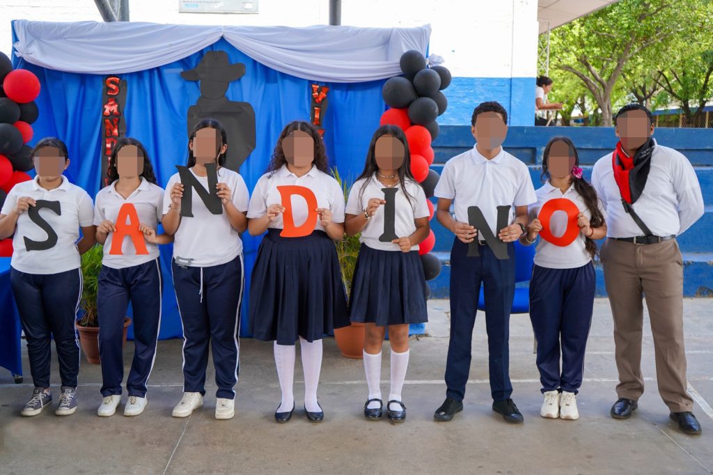 Estudiantes de secundaria forman el apellido Sandino con carteles de los colores partidarios en el patio de un colegio. LA PRENSA / ARCHIVO REDES