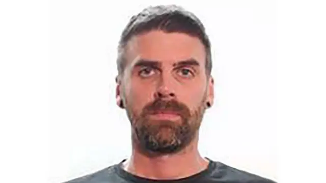 Foto policial de Christopher Malcolm, un hombre con barba que mira a la cámara.