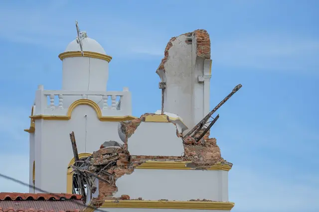 La torre de una iglesia destruida por un terremoto. Está pintanda de blanca.
