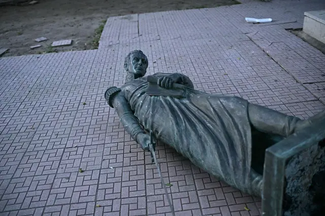 Una estatua de Simón Bolívar yace en el suelo.