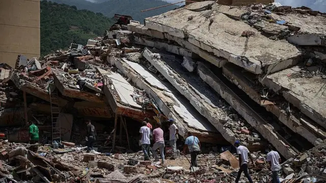 Un edificio destruido en los sismos de Venezuela en junio de 2026. Se ve a personas frente a las ruinas de una edificación en la que se ve pisos aplastados uno sobre otro