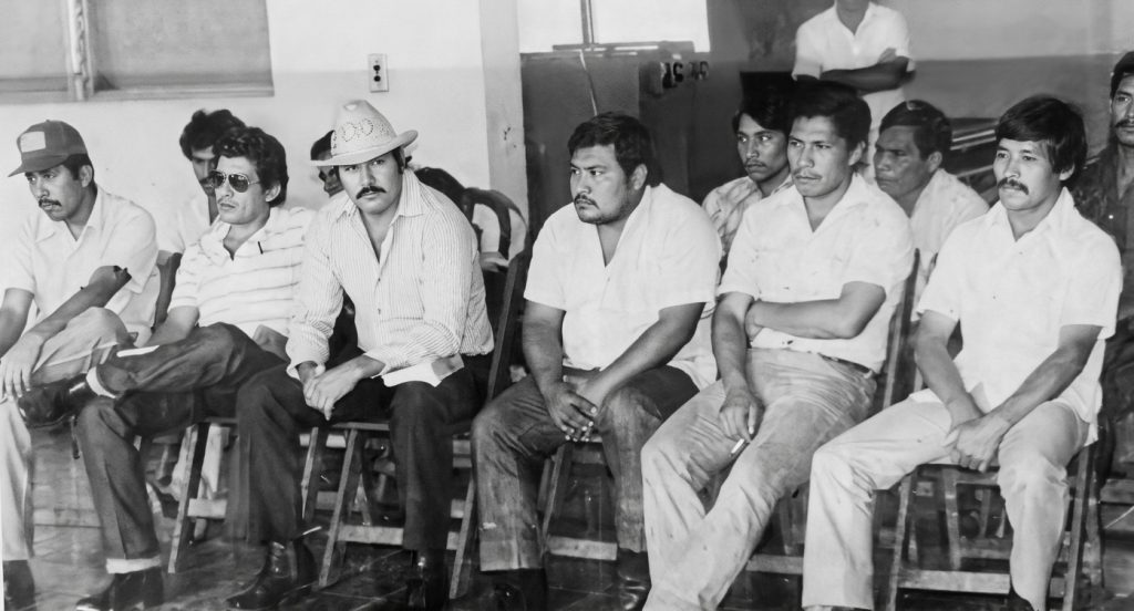 Carlos Barquero (cuarto de izquierda a derecha) junto a doce acusados de cometer crímenes contra la población campesina de Pantasma. En la década de 1990 se convirtió en predicador evangélico y falleció el 22 de octubre de 2020 de un infarto.LA PRENSA / IMAGEN RESTAURADA CON IA