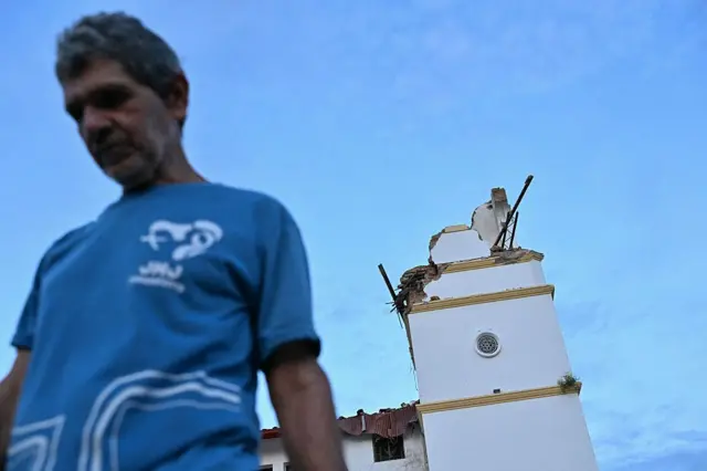 Hombre con camiseta azul camina delante de una iglesia derruida en Panamá.